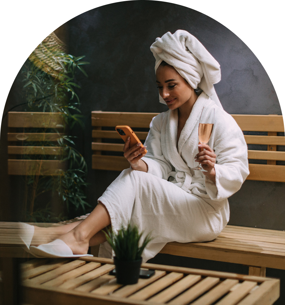 Woman relaxing in robe, using smartphone.