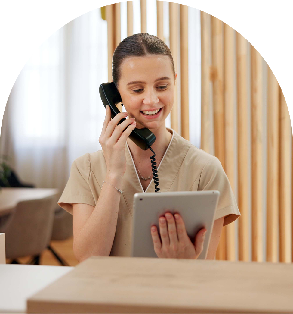 Woman on phone holding a tablet, smiling.